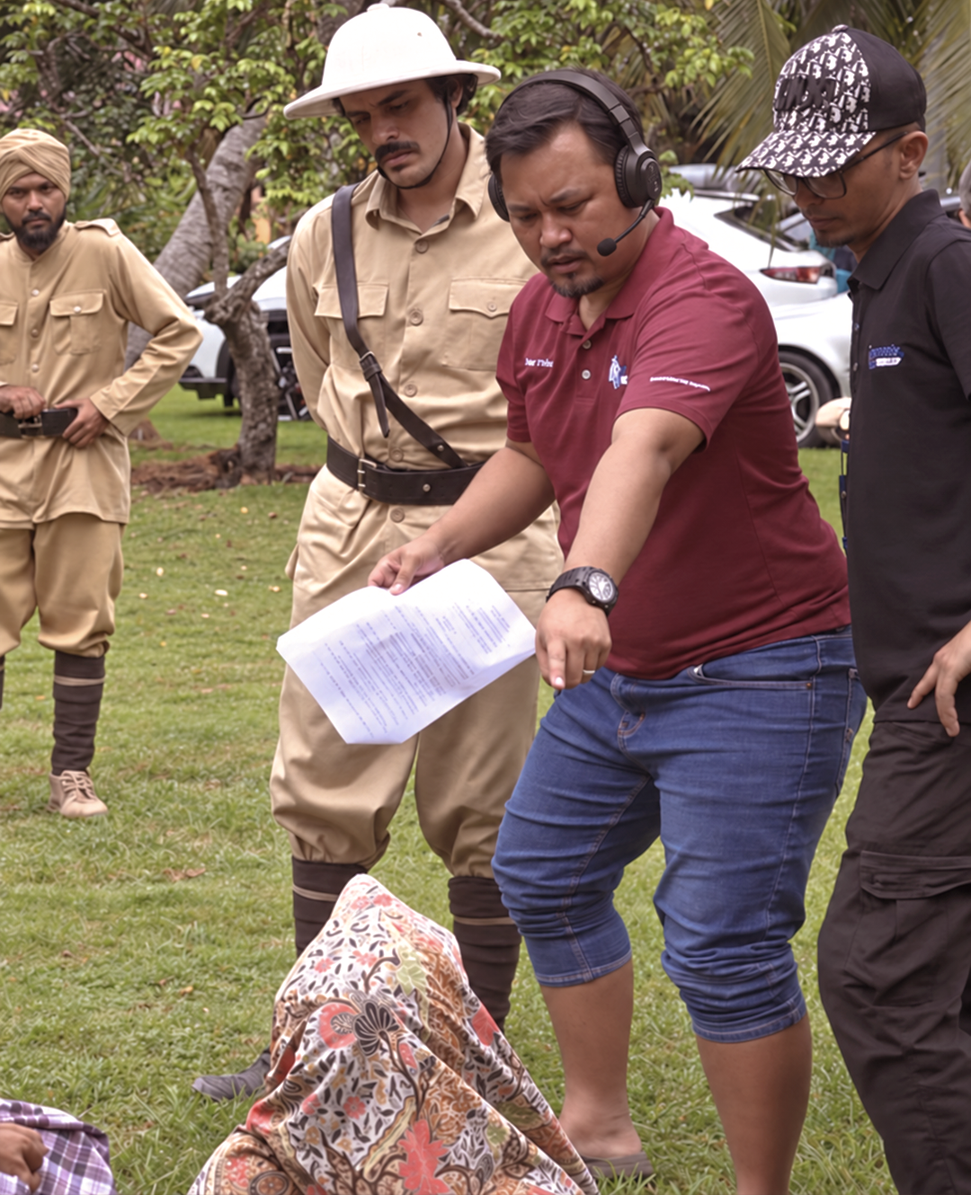Wan Utama directing on set with a headset and script